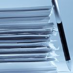 A large stack of white papers leaning against a black and silver pen, shown in a cool blue tint.